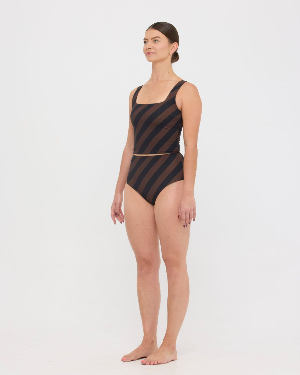 Woman wearing espresso and black rising stripe HUZZAH Ted tank top with high-waisted full-coverage bikini bottoms on white background.