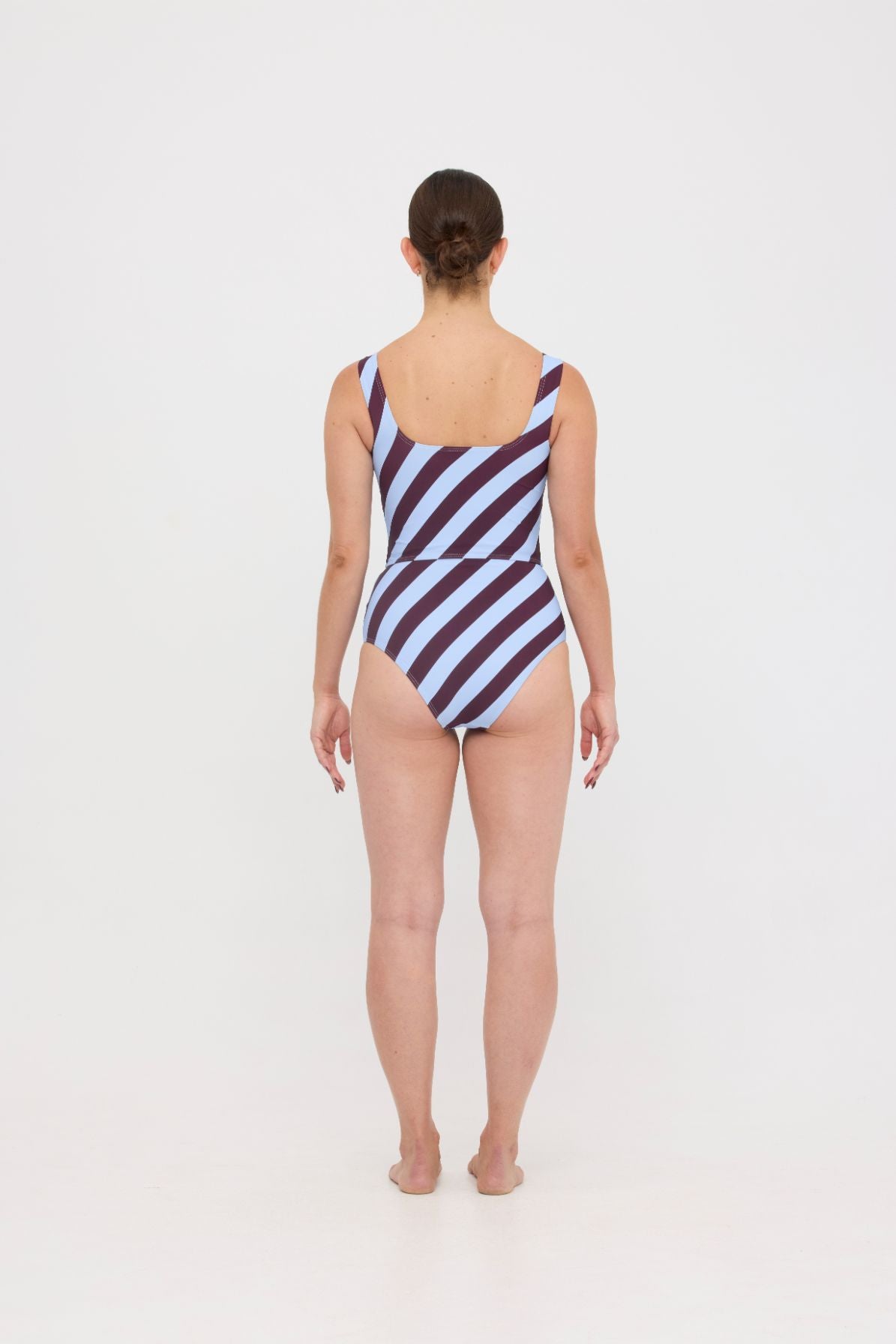 Woman wearing dusty blue and plum rising-stripe HUZZAH Ted tank top with high-waisted full-coverage bikini bottoms on white background.
