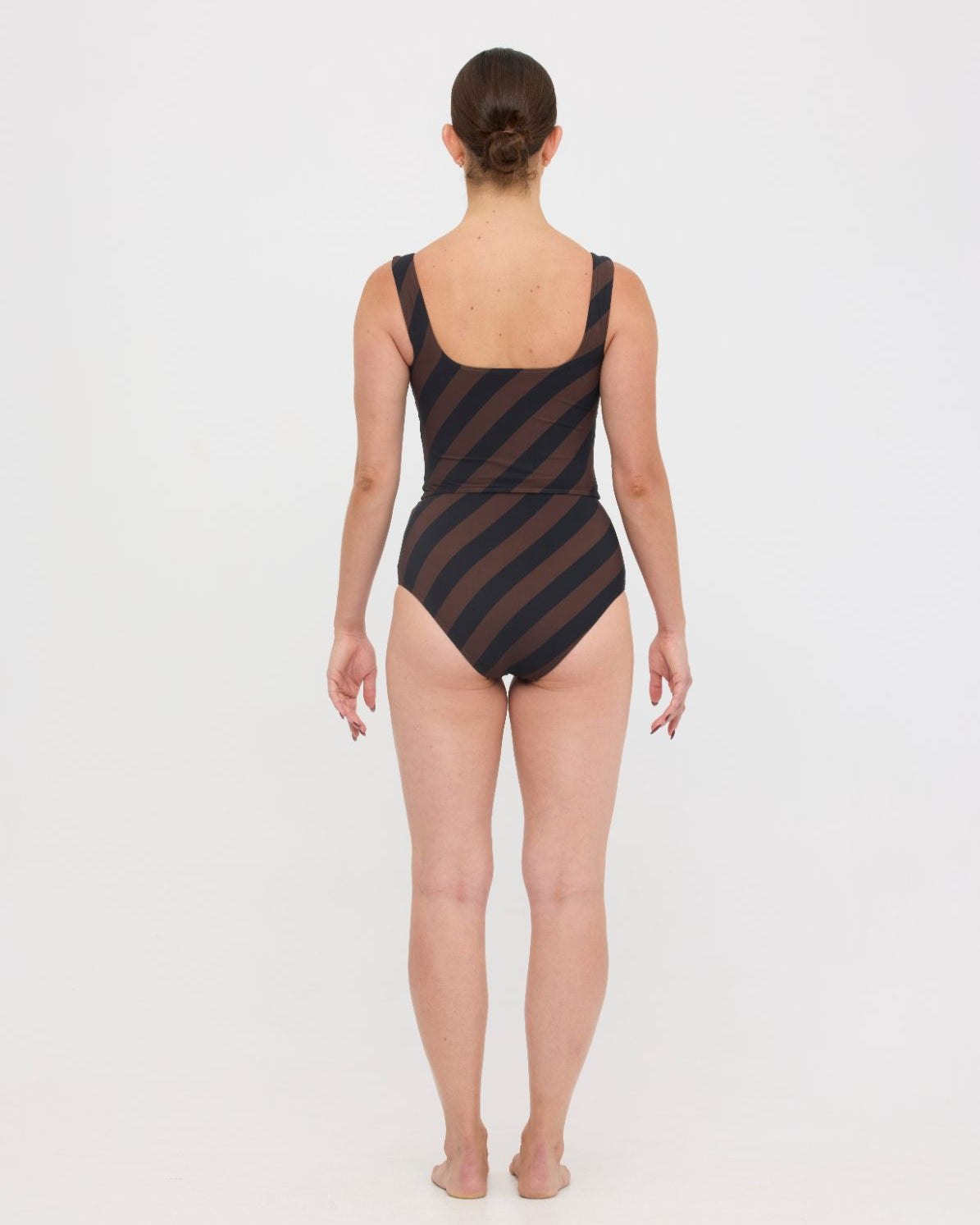 Woman wearing espresso and black rising stripe HUZZAH Ted tank top with high-waisted full-coverage bikini bottoms on white background.