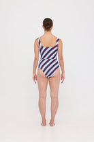 Woman wearing dusty blue and plum rising-stripe HUZZAH Ted tank top with high-waisted full-coverage bikini bottoms on white background.