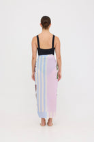 Woman wearing the black HUZZAH Scout sculpting one-piece with a lightweight multi coloured sarong wrapped at the hip, creating a sophisticated swimwear look.