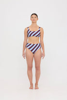 Woman wearing dusty blue and plum rising-stripe HUZZAH Chilli crop top with high-waisted full-coverage bikini bottoms on white background.