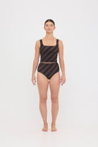 Woman wearing espresso and black rising stripe HUZZAH Ted tank top with high-waisted full-coverage bikini bottoms on white background.