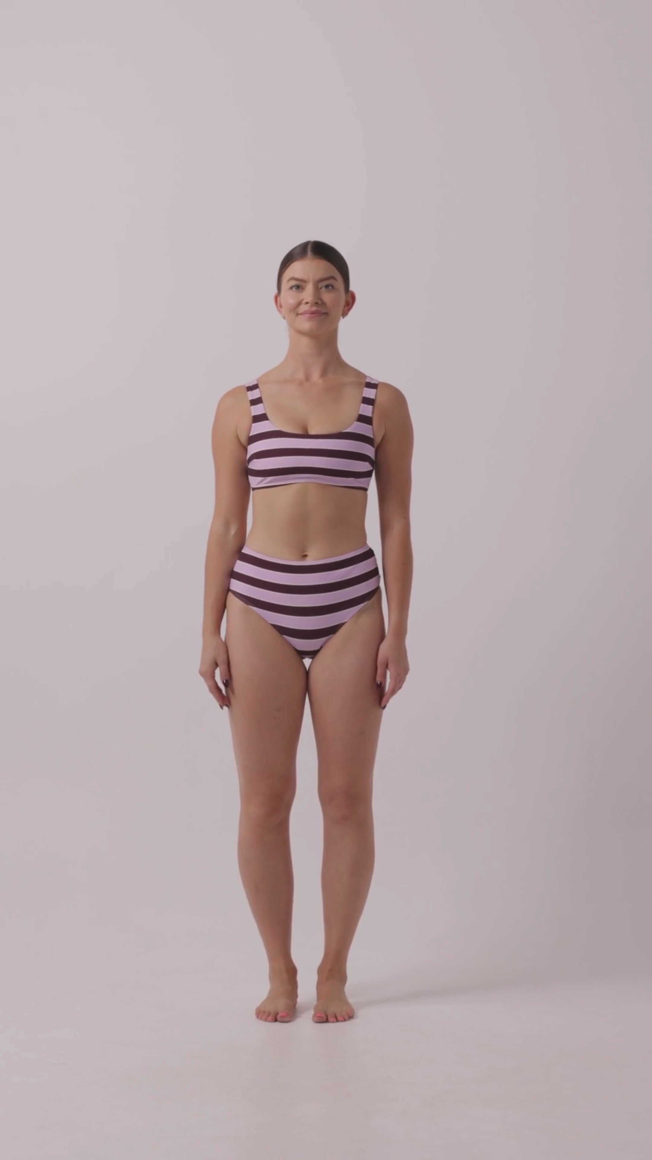 Model in Violet and Plum mixed-stripe HUZZAH Chilli crop bikini top paired with mid-waisted full-coverage bottoms