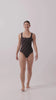 Model wearing the espresso and black rising stripe HUZZAH Cat one-piece swimsuit with sculpting fit and clean lines, photographed against a plain background